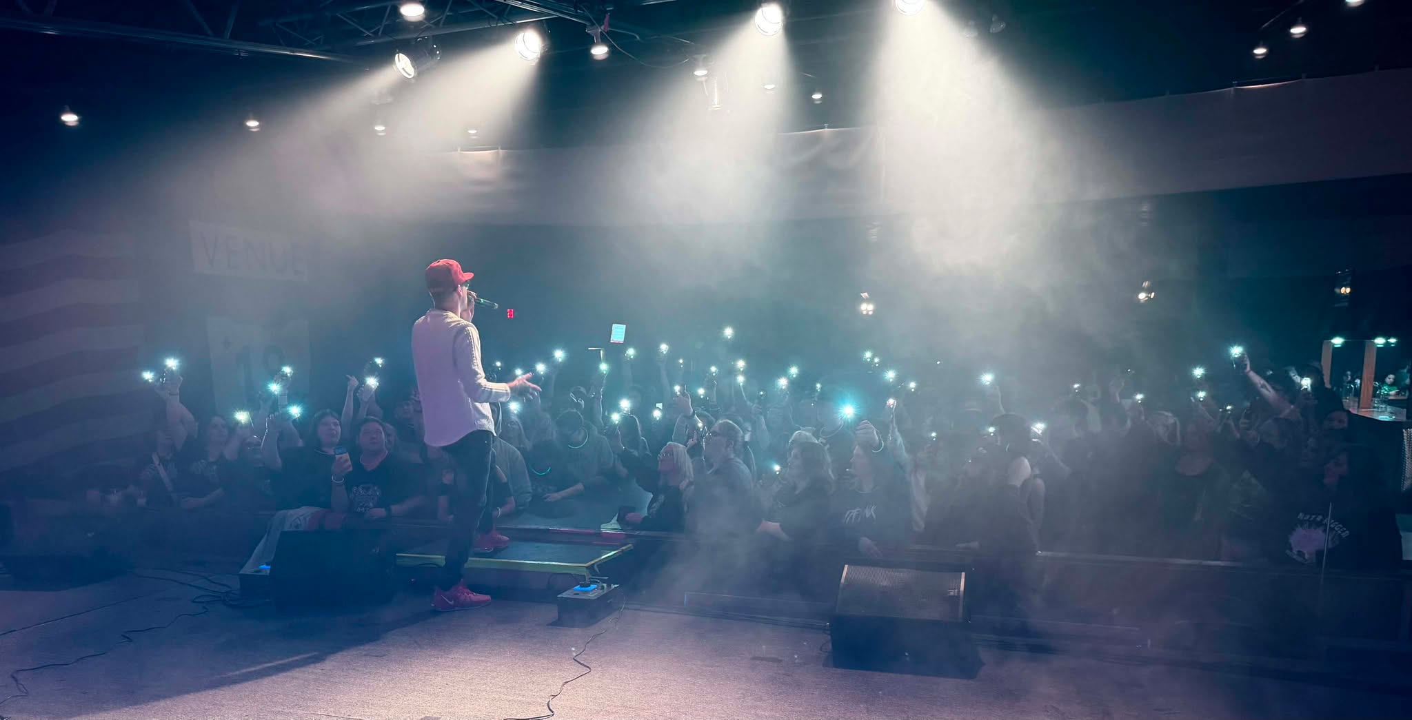 Brian Durst on stage facing a crowd holding up phone lights.