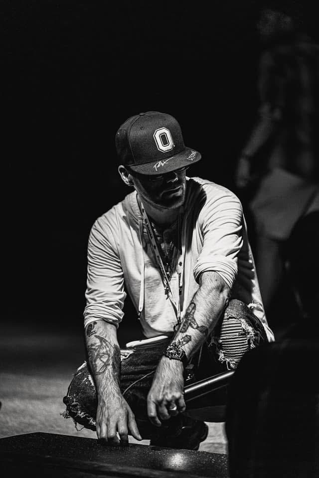Black and white portrait of Brian Durst crouching under dramatic light.