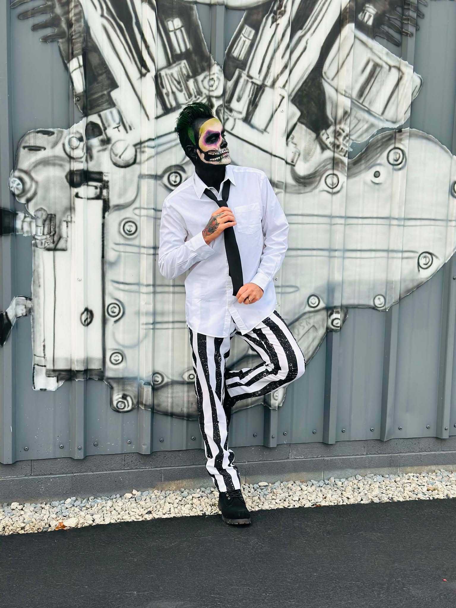 Brian Durst standing in a white outfit against an industrial wall.